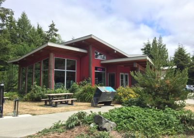 Building with red cladding, glazing and a picnic area