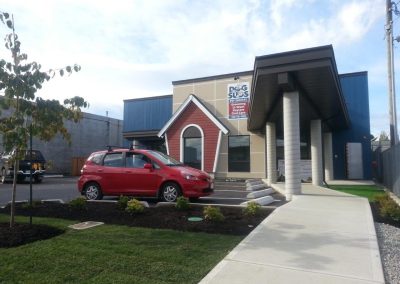 Commercial building with tall columns and a red car out front
